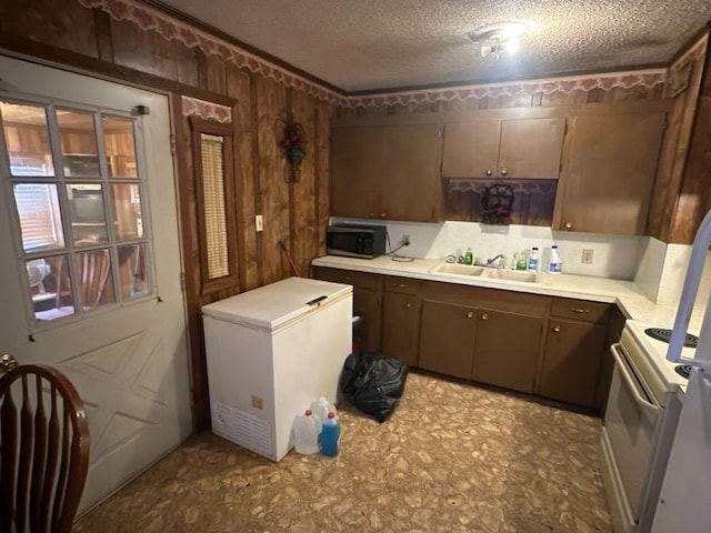 kitchen with sink, electric range, fridge, and a textured ceiling