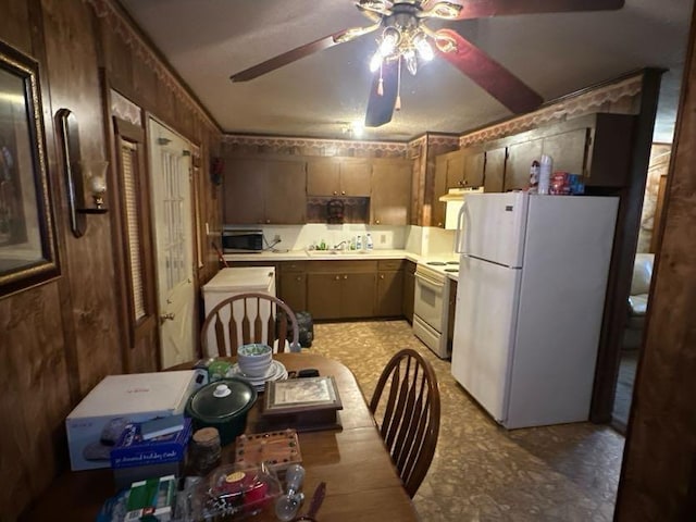 kitchen with sink, white appliances, wooden walls, and ceiling fan