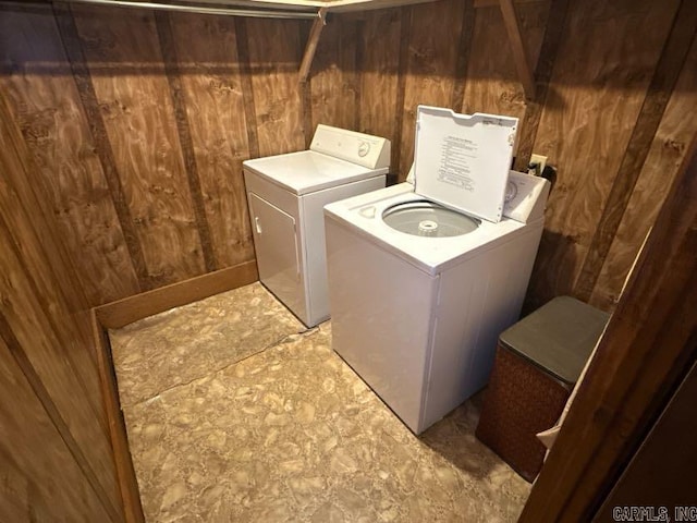 clothes washing area featuring washing machine and dryer and wood walls