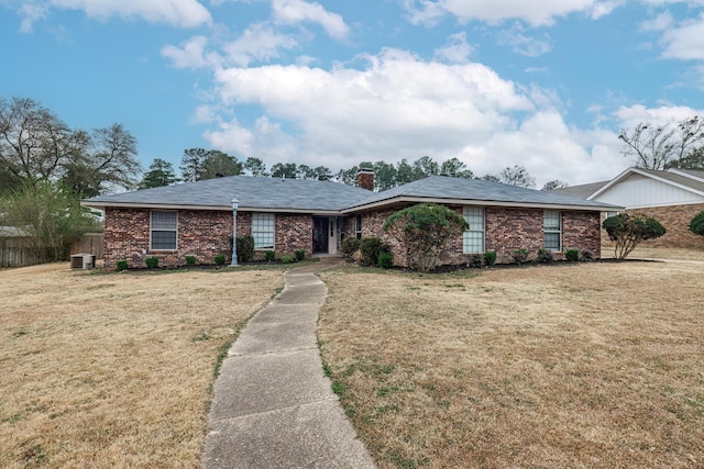 ranch-style home with central air condition unit and a front lawn