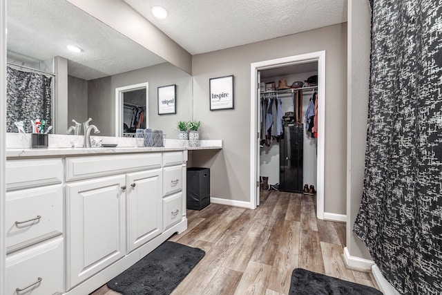 bathroom with vanity, wood-type flooring, a textured ceiling, and a shower with curtain