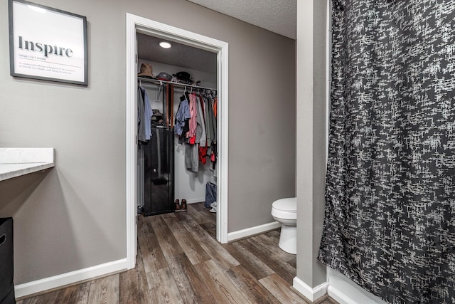 bathroom featuring wood-type flooring, toilet, and a textured ceiling