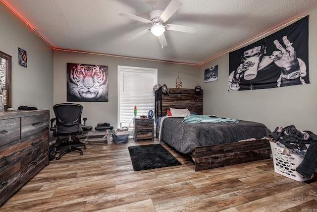 bedroom featuring crown molding, hardwood / wood-style floors, ceiling fan, and a textured ceiling