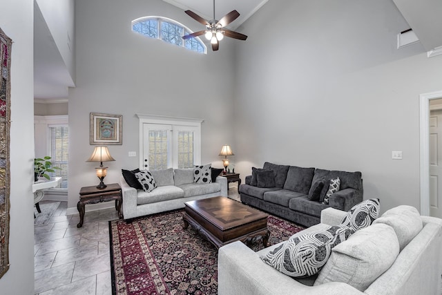 living room with ceiling fan, ornamental molding, and a high ceiling