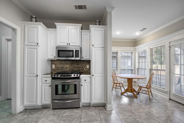 kitchen with white cabinetry, backsplash, crown molding, and stainless steel appliances