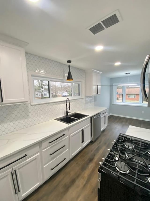 kitchen with dishwasher, white cabinetry, sink, hanging light fixtures, and light stone countertops