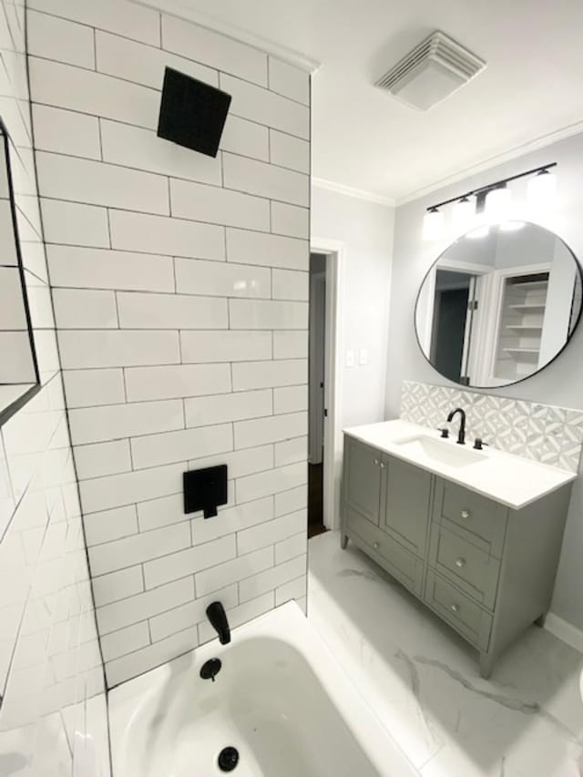 bathroom with ornamental molding, vanity, backsplash, and tiled shower / bath