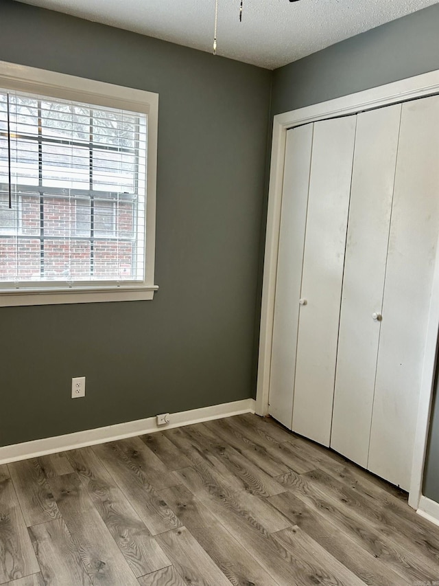 unfurnished bedroom featuring light hardwood / wood-style floors, a closet, and a textured ceiling