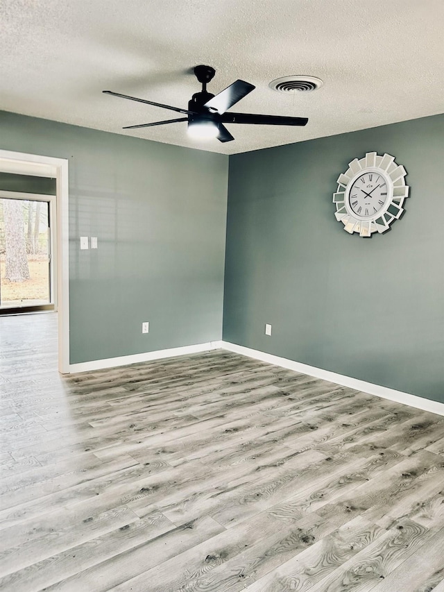 empty room with ceiling fan, light hardwood / wood-style floors, and a textured ceiling