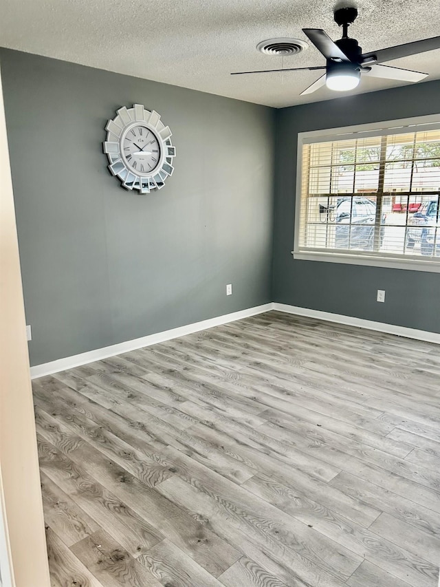 empty room featuring a textured ceiling, light hardwood / wood-style flooring, and ceiling fan