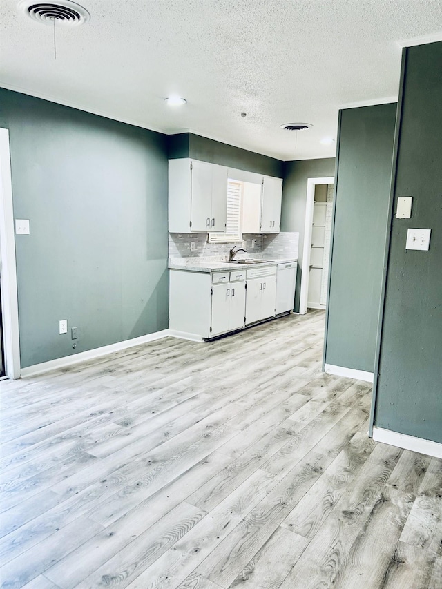 kitchen with white cabinetry, sink, decorative backsplash, white dishwasher, and light hardwood / wood-style floors