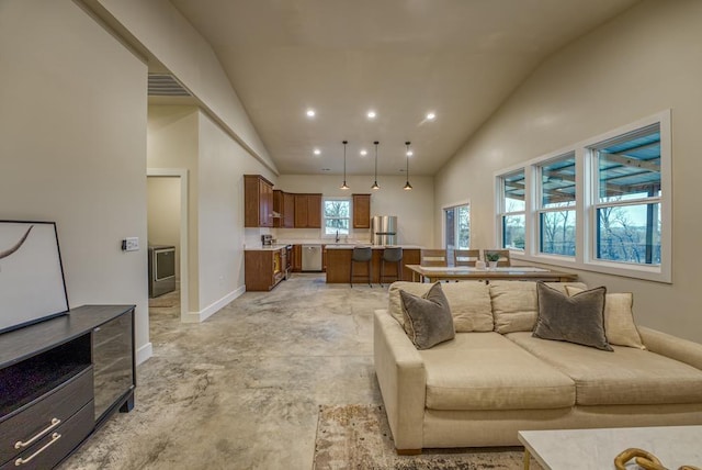 living room featuring washer / clothes dryer, sink, and high vaulted ceiling