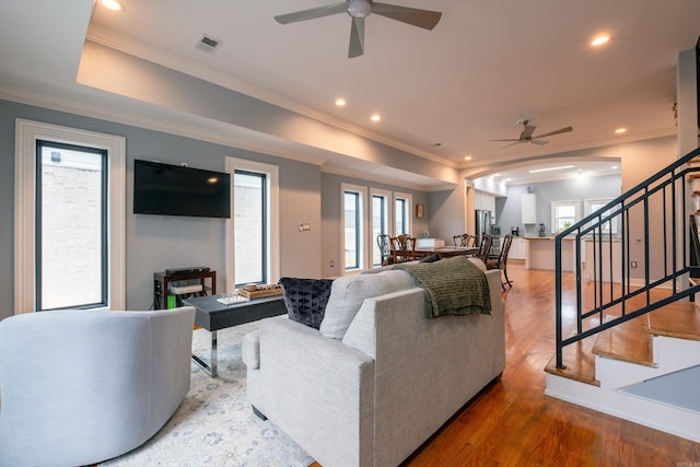 living room with wood-type flooring, a healthy amount of sunlight, ceiling fan, and crown molding