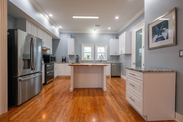 kitchen featuring sink, white cabinetry, stainless steel appliances, ornamental molding, and light wood-type flooring