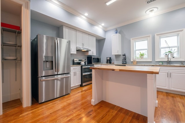 kitchen with butcher block countertops, sink, appliances with stainless steel finishes, white cabinetry, and light hardwood / wood-style floors