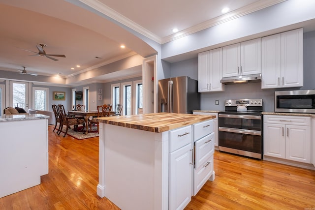 kitchen featuring white cabinets, wooden counters, a center island, stainless steel appliances, and light wood-type flooring