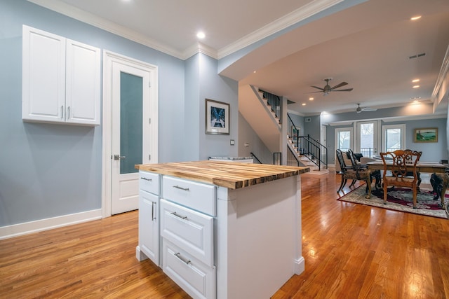 kitchen with white cabinetry, wood counters, a kitchen island, and light hardwood / wood-style flooring