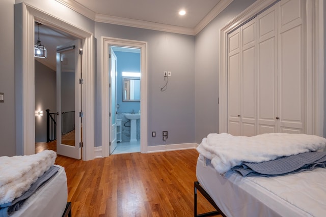 bedroom with crown molding, connected bathroom, light hardwood / wood-style flooring, and a closet