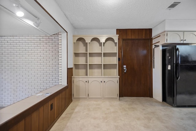 kitchen with a textured ceiling and black fridge