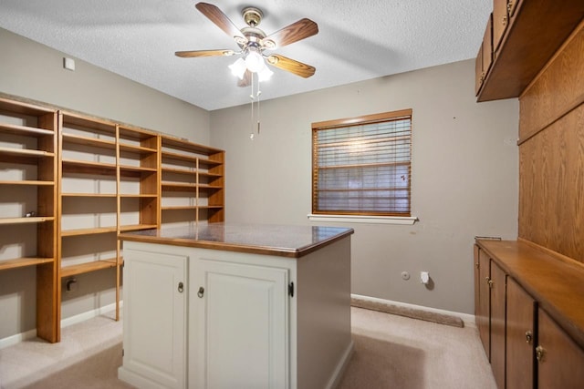 interior space with ceiling fan, built in desk, light carpet, and a textured ceiling