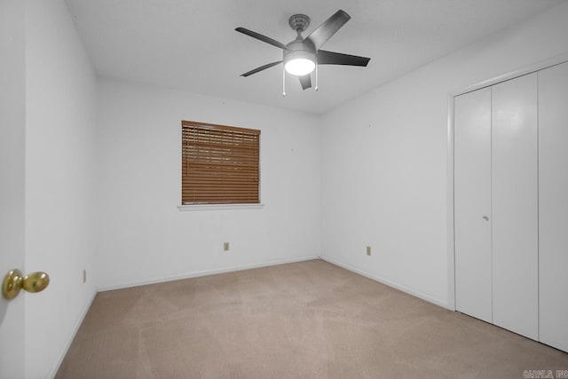 unfurnished bedroom with light colored carpet, a closet, and ceiling fan