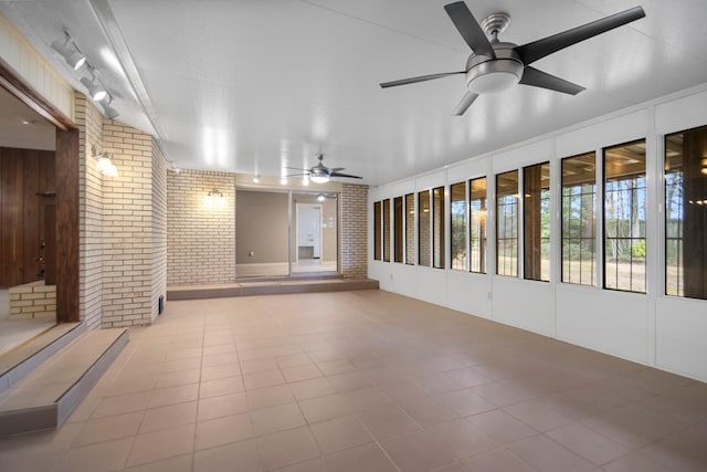 tiled spare room with brick wall and ceiling fan