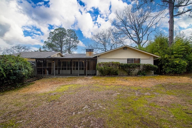 rear view of property featuring a yard and a sunroom