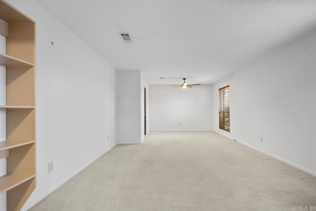 unfurnished room with ceiling fan, light carpet, and a textured ceiling