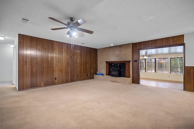 unfurnished living room with a textured ceiling, light carpet, and wood walls