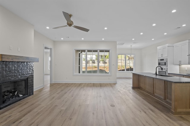 kitchen with brown cabinets, open floor plan, white cabinetry, and decorative light fixtures