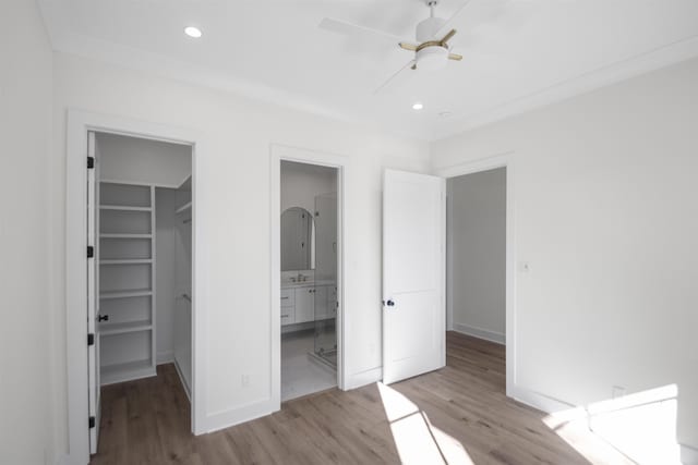 unfurnished bedroom featuring recessed lighting, a closet, a spacious closet, light wood-style floors, and baseboards