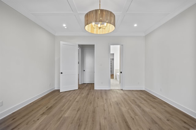 unfurnished room featuring light wood-style floors, ornamental molding, a chandelier, coffered ceiling, and baseboards