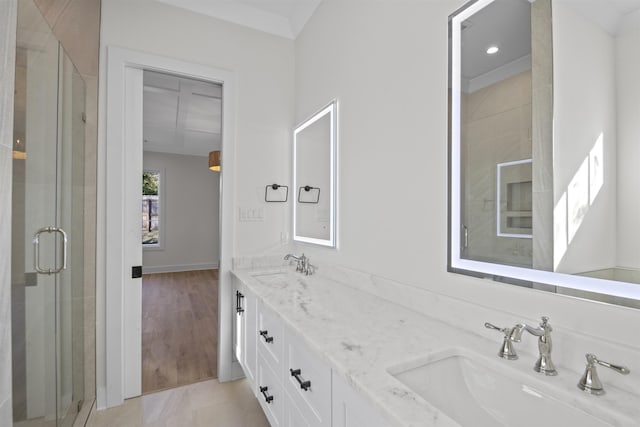 full bathroom with crown molding, a sink, a shower stall, and double vanity