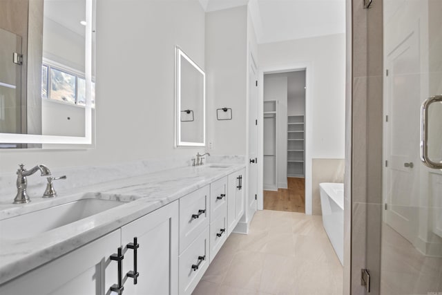 full bathroom featuring double vanity, a stall shower, a sink, and a soaking tub