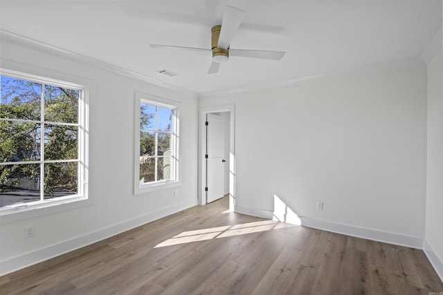 unfurnished room featuring wood finished floors, a ceiling fan, visible vents, baseboards, and ornamental molding