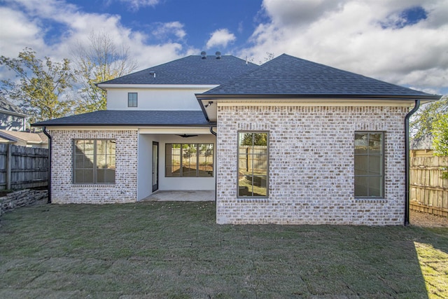 back of property with a yard, brick siding, and fence