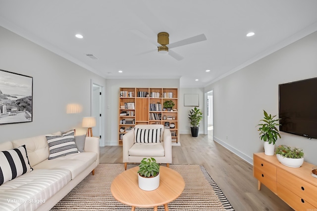 living room featuring ceiling fan, recessed lighting, baseboards, light wood-style floors, and ornamental molding