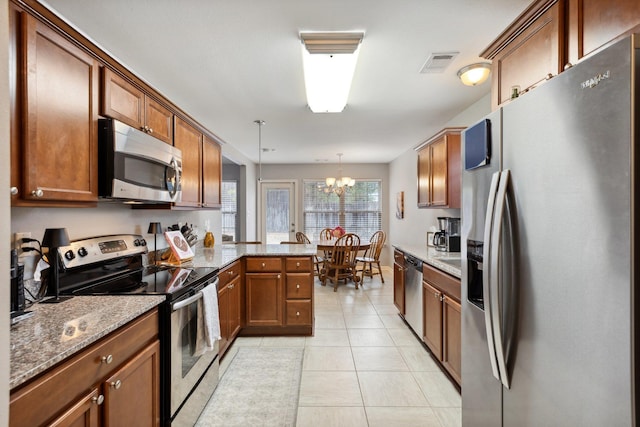 kitchen featuring pendant lighting, light tile patterned floors, stainless steel appliances, light stone counters, and kitchen peninsula