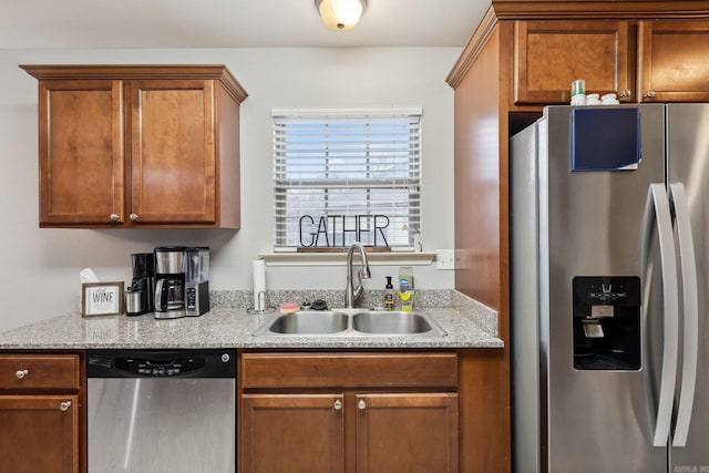 kitchen featuring stainless steel appliances, sink, and light stone counters