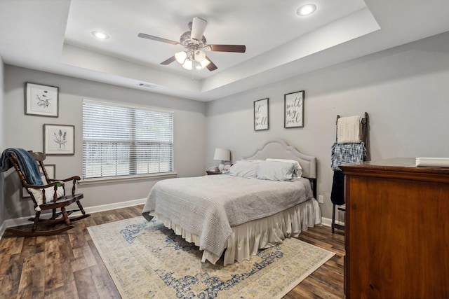 bedroom featuring dark hardwood / wood-style flooring, a raised ceiling, and ceiling fan