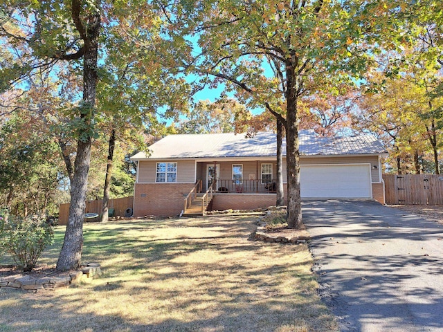 ranch-style house featuring a garage, a front yard, and covered porch