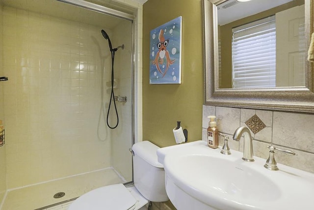 bathroom with sink, a tile shower, backsplash, and toilet