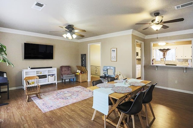 dining room featuring dark wood-type flooring, ornamental molding, and ceiling fan