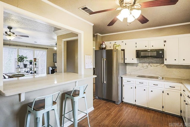 kitchen featuring dark hardwood / wood-style floors, ornamental molding, black appliances, white cabinets, and a kitchen bar