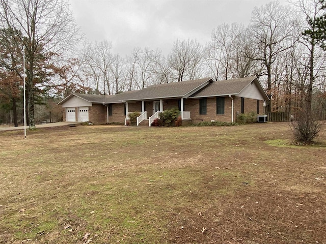 ranch-style home featuring a porch, a garage, a front lawn, and central air condition unit