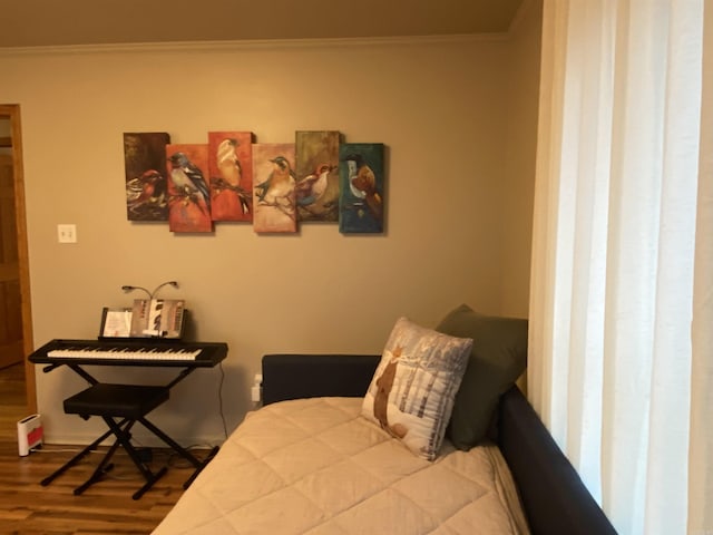 bedroom featuring hardwood / wood-style flooring, a baseboard radiator, and ornamental molding