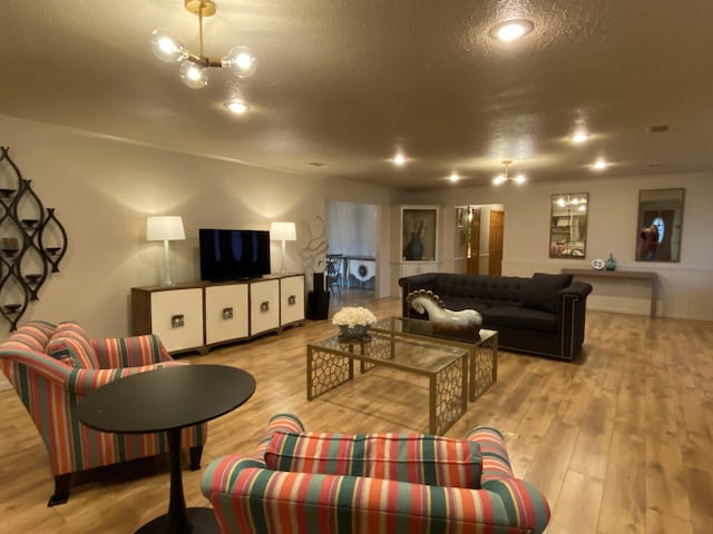 living room with an inviting chandelier, light hardwood / wood-style floors, and a textured ceiling