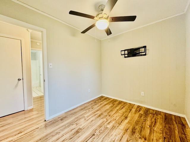 empty room with ornamental molding, ceiling fan, and light wood-type flooring