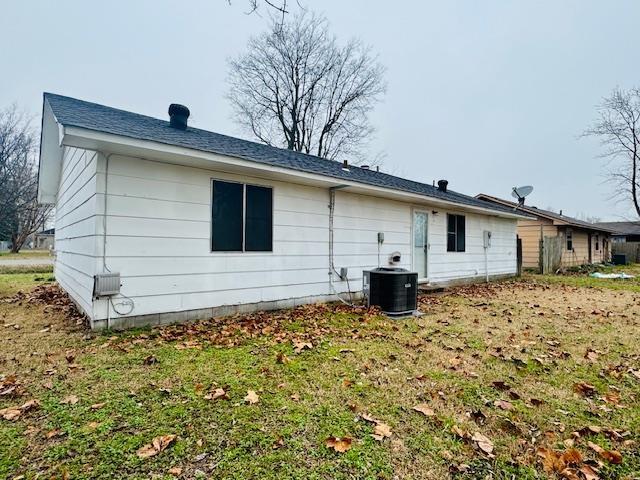 back of house featuring cooling unit and a lawn