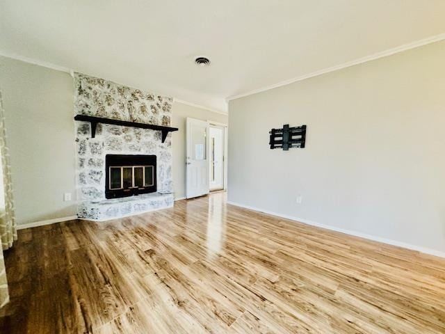 unfurnished living room with hardwood / wood-style flooring, ornamental molding, and a large fireplace